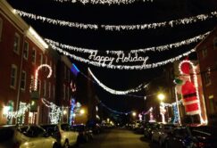 A festive holiday guide to the Christmas lights adorning the charming streets of Federal Hill in Baltimore, where parked cars add to the picturesque scenery.