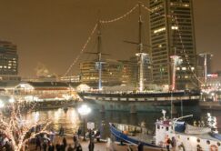 A boat docked in Baltimore's Inner Harbor with holiday lights illuminating its voyage.